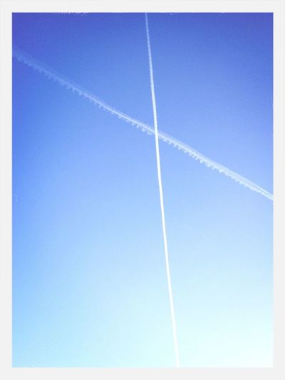 Low angle view of vapor trails against blue sky