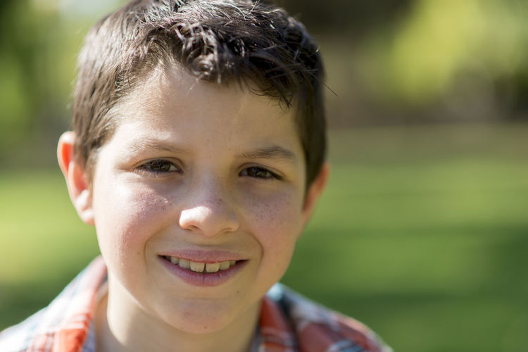 Portrait of boy smiling while sitting at park