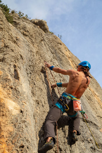 Low angle view of shirtless man climbing rock