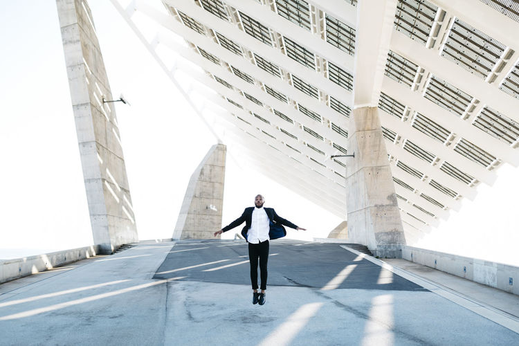 Vital businessman jumping under solar panels