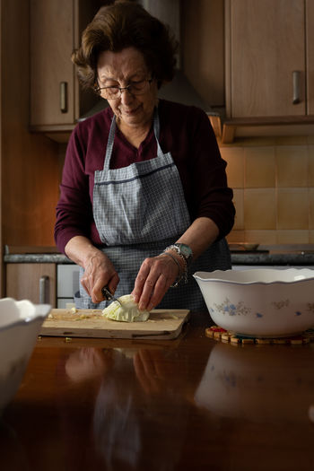 Housewife chopping raw leaves of cabbage while cooking traditional spanish cocido madrileno