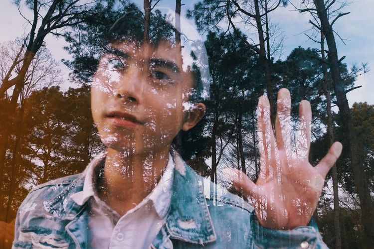 Double exposure of young man and trees