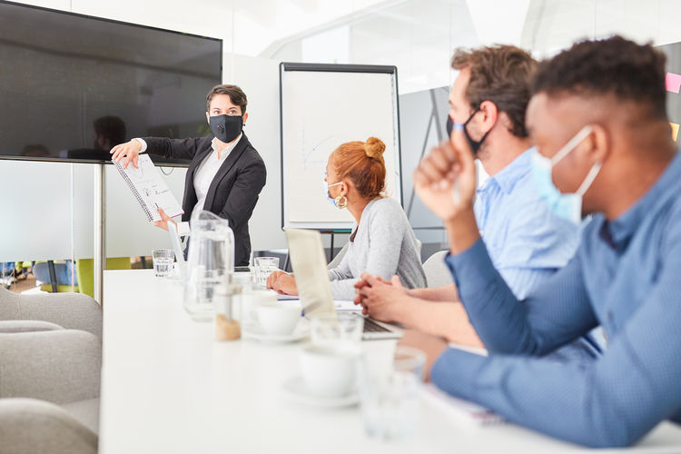 Businesswoman wearing mask giving presentation at board room