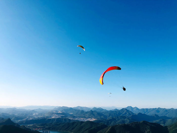 Kite flying over mountain against blue sky