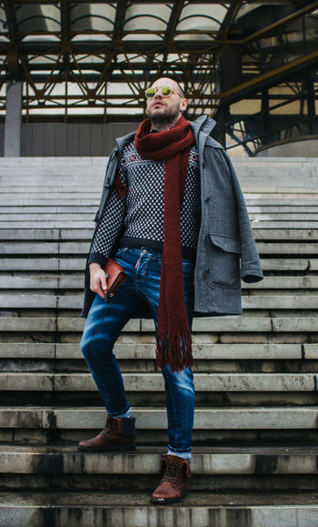 Man wearing warm clothing standing on steps outdoors