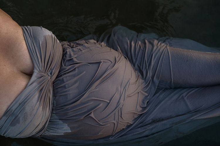 Low section of pregnant woman lying bathing in lake