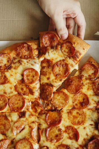 Close-up of hand holding pizza