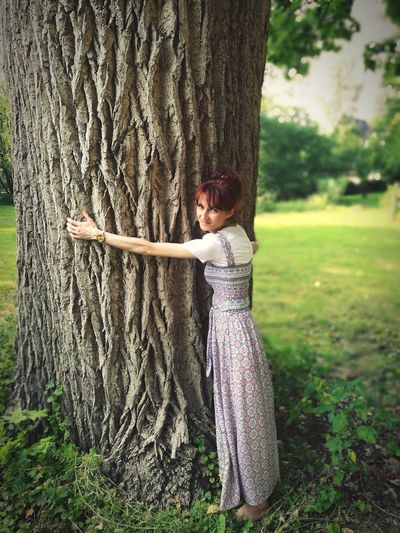 Side view of girl standing on tree trunk