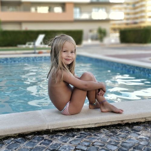 Portrait of happy girl sitting in poolside