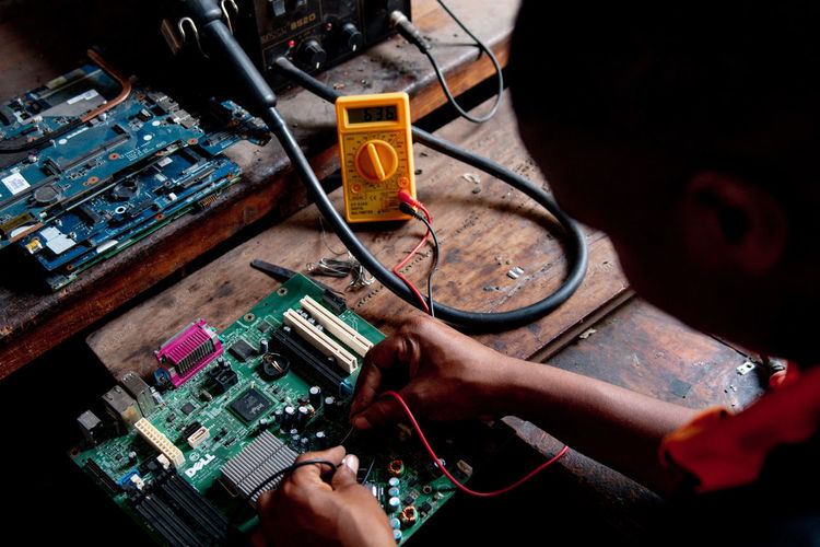 Young adult repairing a computer motherboard in a workshop