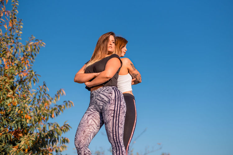 Low angle view of women in sports clothing against clear sky