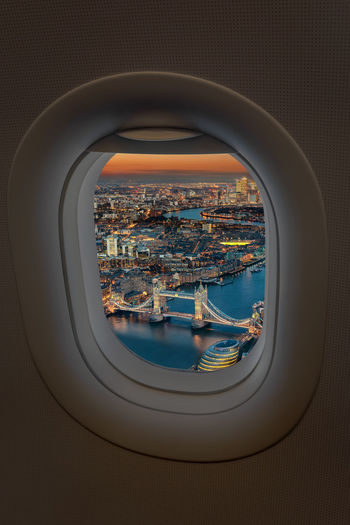Tower bridge over thames river in city seen through airplane window at dusk