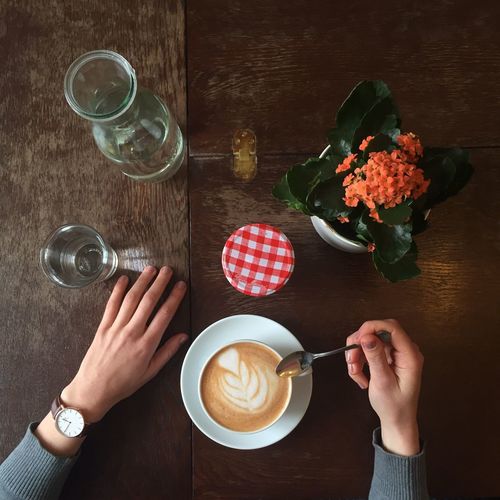Close-up of hand holding coffee cup on table