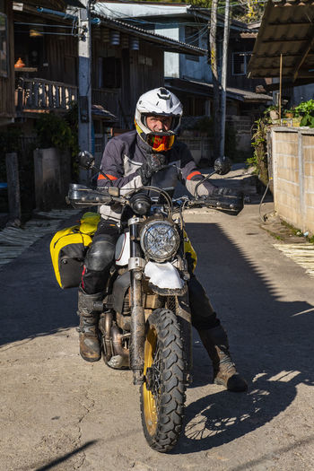 Man stopping on road with his motorcycle in thai village