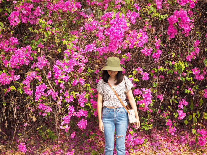 Full length of woman standing by pink flowering plants