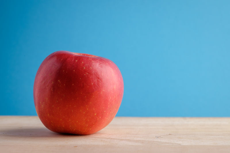 Close-up of apple on table against blue background