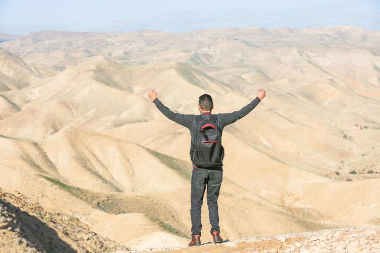 Man with arms outstretched standing on land