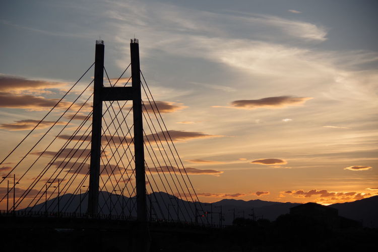 Low angle view of suspension bridge against sky during sunset