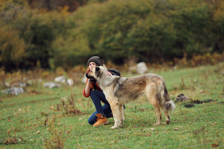 Full length of woman with dog on field