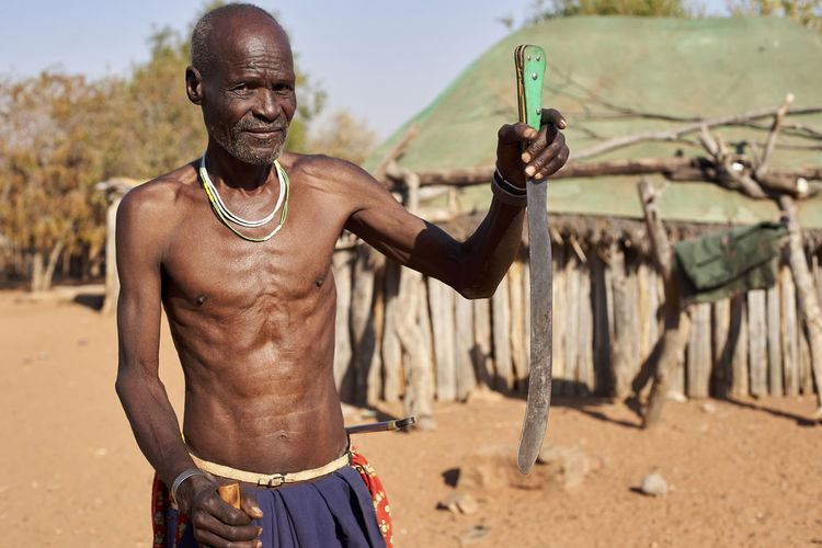 Traditional mudimba tribe man holding a stick and his knife, canhimei, angola.