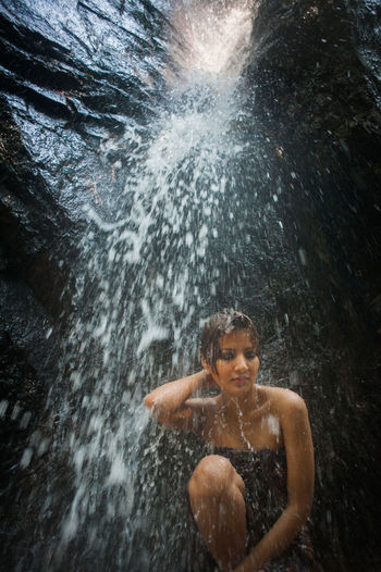 Mid adult woman bathing in waterfall