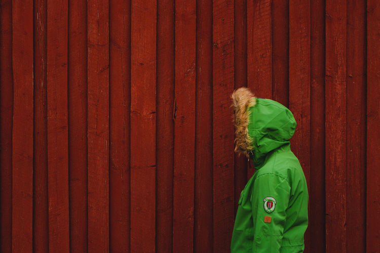 Rear view of child standing on red wooden door