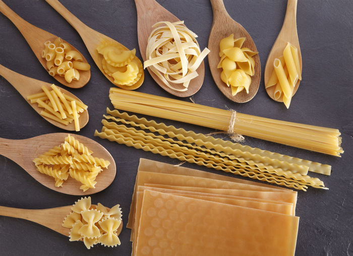 Close-up of raw pasta and wooden spoon on table