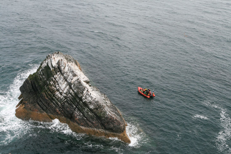 High angle view of rock in sea with inflatable boat next to it