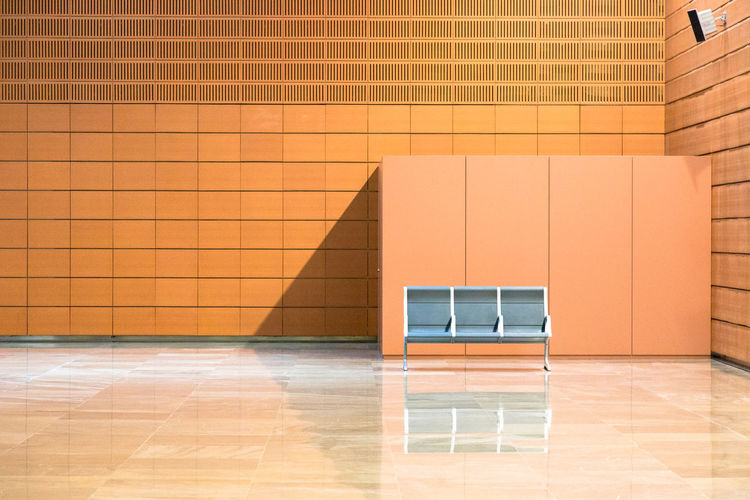 Empty chairs against orange wall