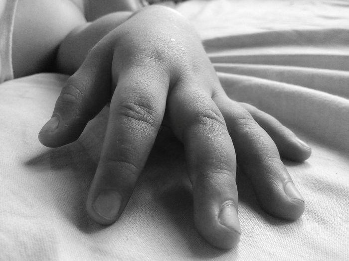Cropped hand of child on bed