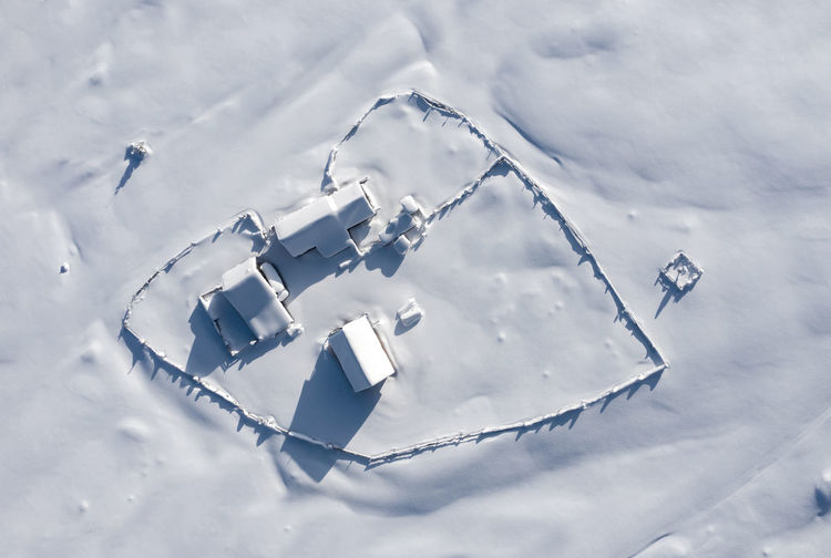 Snow covered remote, heart shaped homestead in the mountains. aerial drone above view
