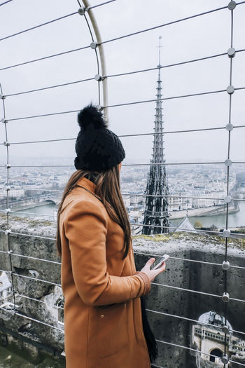 Side view of woman looking at tower from observation point in city during winter