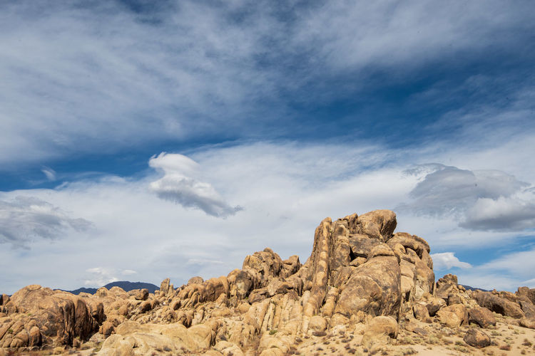Rock formations on landscape against sky with cloud formations