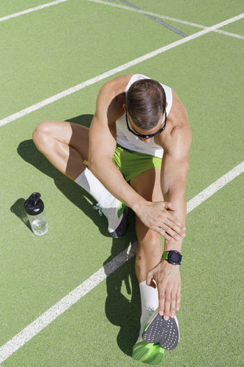 Athlete doing stretching exercise sitting on ground