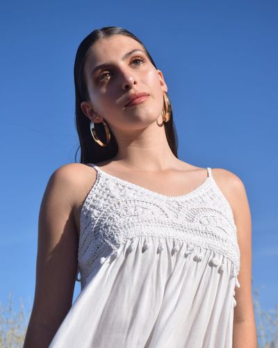 Low angle portrait of young woman standing against clear blue sky