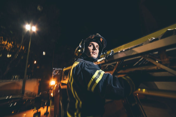 Firefighter riding on outside of fire truck at night