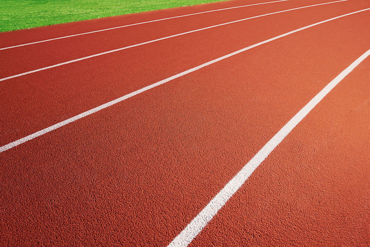 Red running track at stadium with border lanes