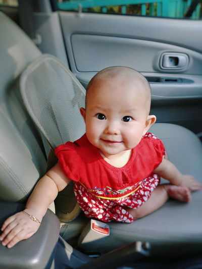 High angle portrait of cute baby girl sitting on vehicle seat in car