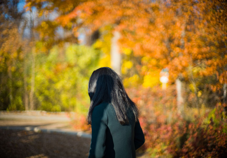 Midsection of woman standing against trees during autumn