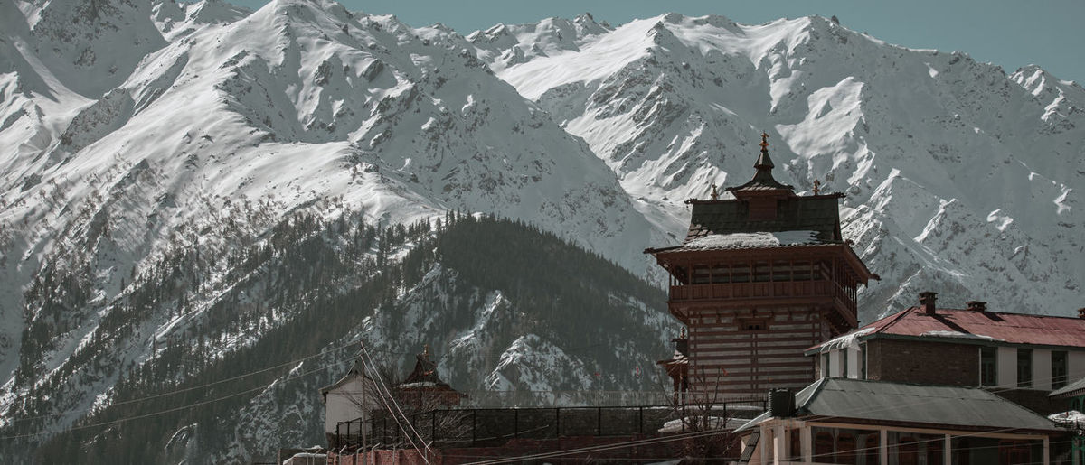 Scenic view of ancient temple against snow covered mountains and clear sky