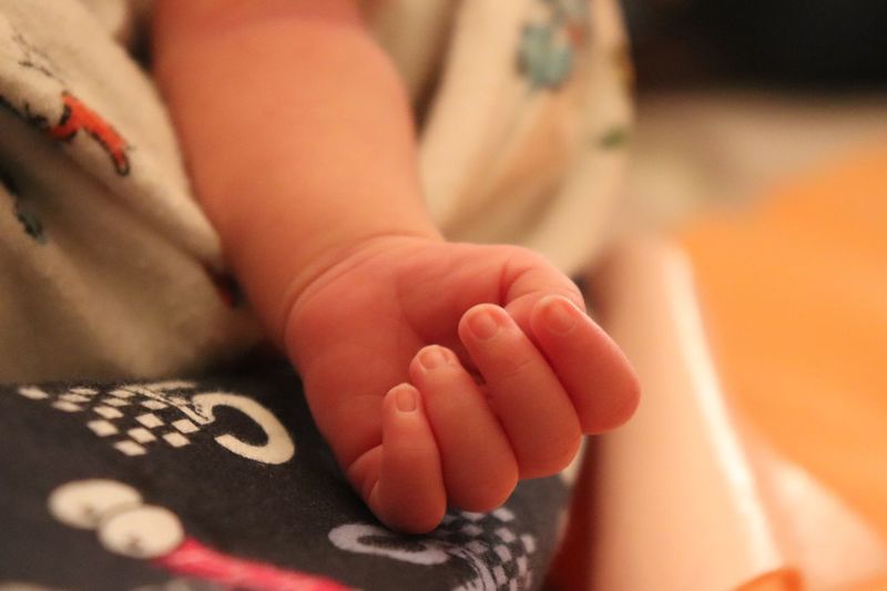 Close-up of baby hand on bed at home