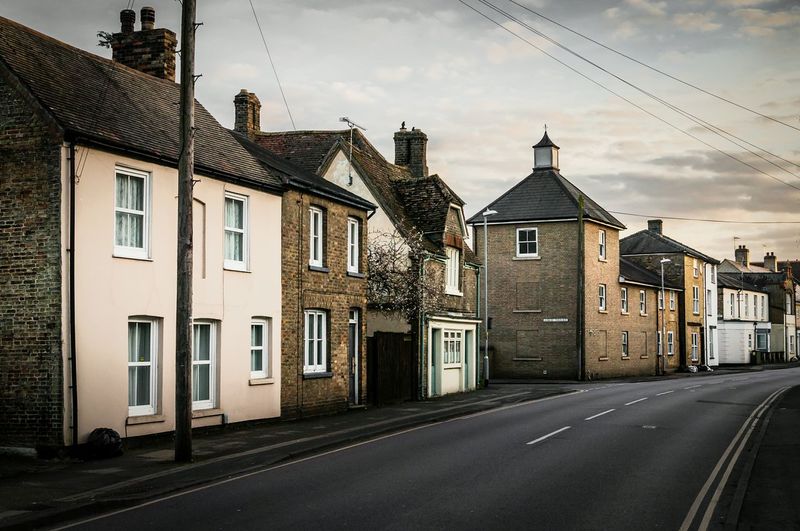 Empty road by houses in city