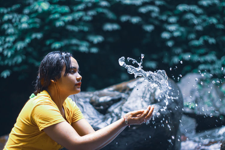 Young woman splashing water in park