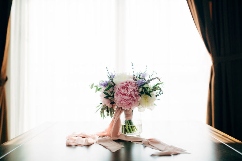Flower vase on table against window