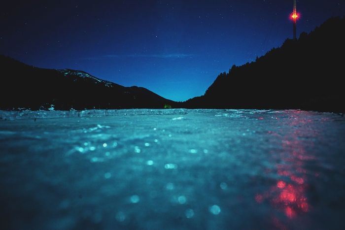 Surface level of lake with mountains in background at night