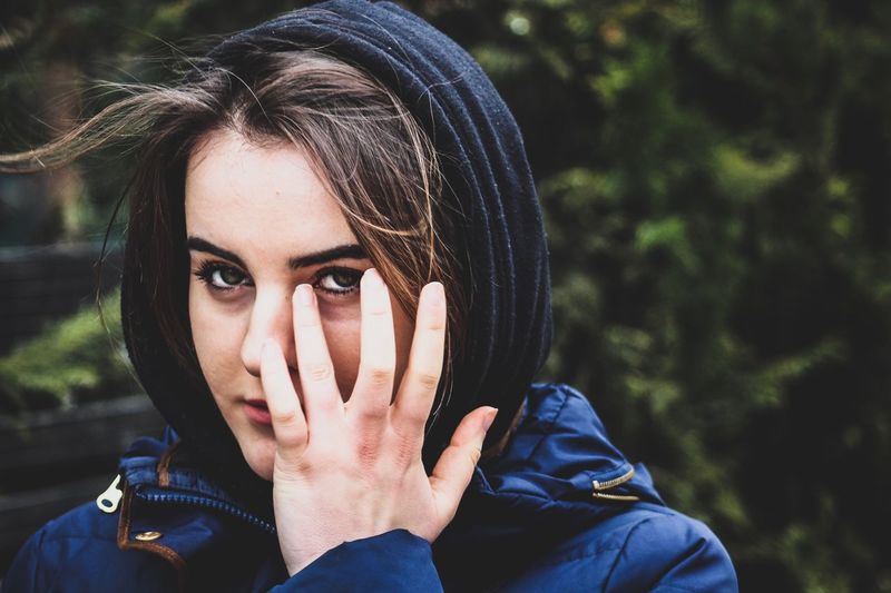 Close-up portrait of beautiful young woman with hand on face
