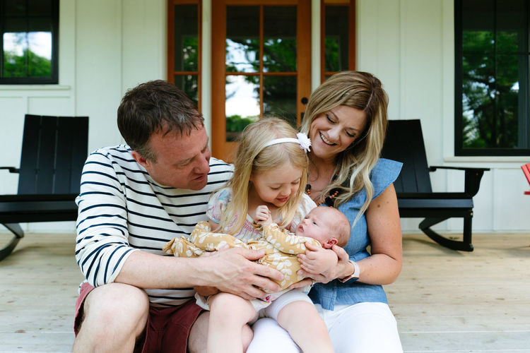 A new family sitting together on a modern farmhouse porch