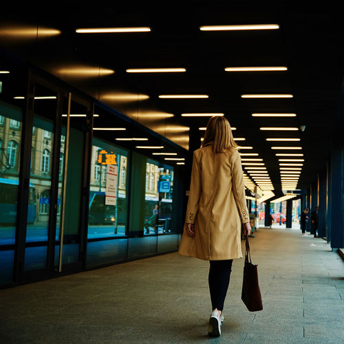 Woman in coat walks at city street with bag