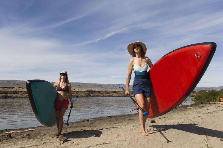 Two women carry their sups from the columbia river in oregon.