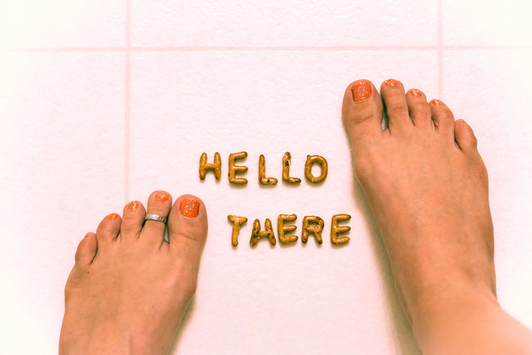 Low section of woman with hello there text on tiled floor